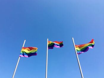 Low angle view of flags against clear blue sky