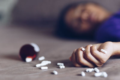 Close-up of woman with medicines lying at home