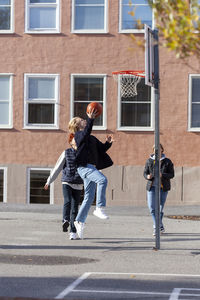 Teenage boys playing basketball in schoolyard