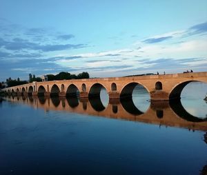 Arch bridge over river against sky