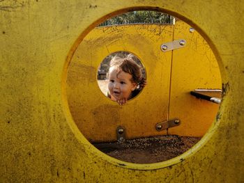 Cute baby boy looking through hole of play equipment