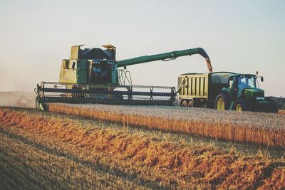 Tractor harvesting in farm against sky