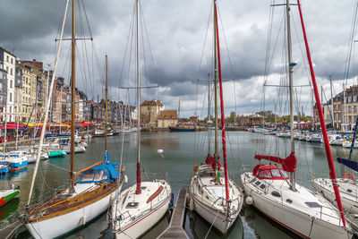 Sailboats moored at harbor against sky