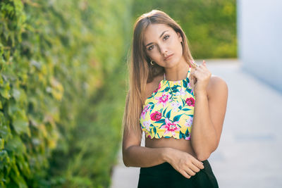 Portrait of a beautiful young woman standing against blurred background