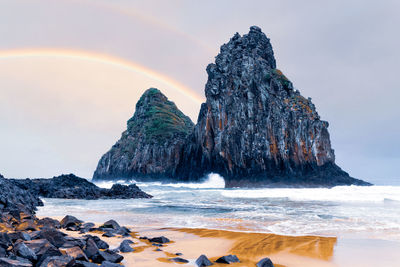 Rock formation on beach against sky