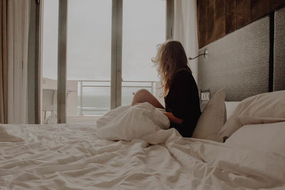 Woman sitting on bed at home