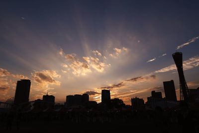 Silhouette of buildings against cloudy sky at sunset