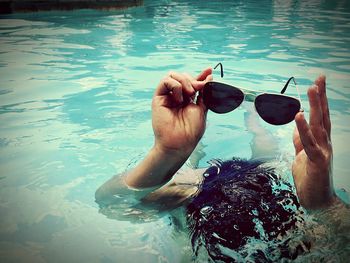 Close-up of hand holding sunglasses in water
