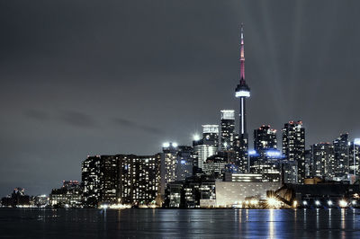 Illuminated cityscape and cn tower by river at night