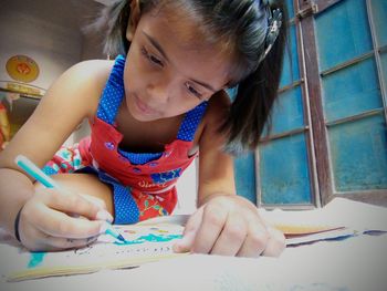 Close-up of girl coloring on book at home