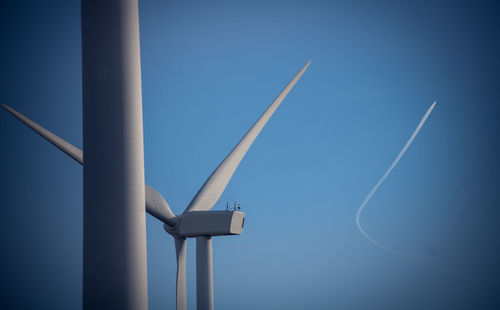 Low angle view of wind turbine against blue sky