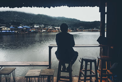 Rear view of man looking at river from cafe