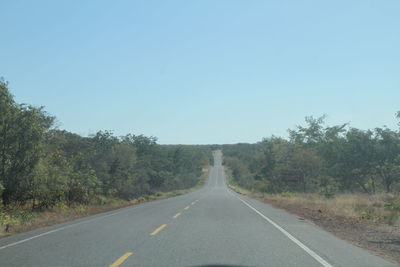 Road amidst trees against clear sky