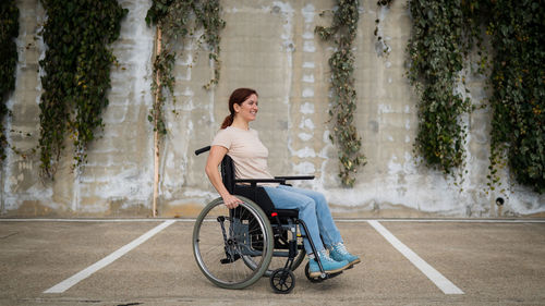 Disabled woman sitting on wheelchair against wall