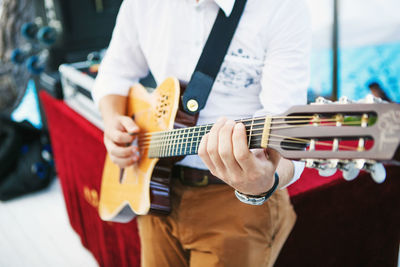 Midsection of man playing guitar