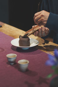 Midsection of person holding ice cream on table