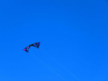 Low angle view of kite flying against clear blue sky