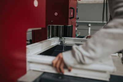 Cropped hands of manual worker making window frame at factory