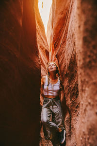 Young woman exploring narrow slot canyons in escalante, during summer