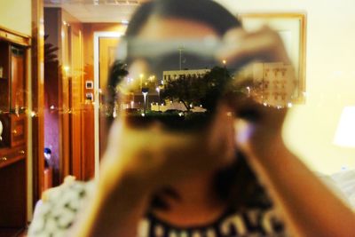 Reflection of man photographing in illuminated mirror