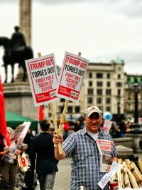 Portrait of man holding placards with text during text during protest in city