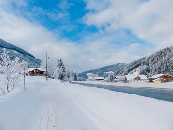 Road by snow covered mountain against sky