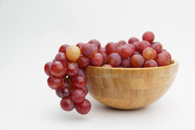 Close-up of grapes in bowl against white background