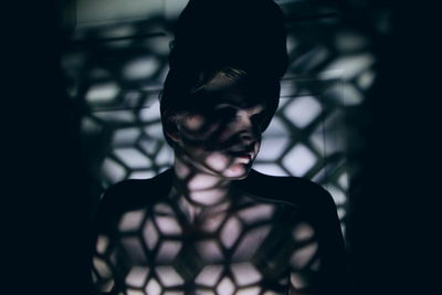 Topless young woman standing with shadow in darkroom