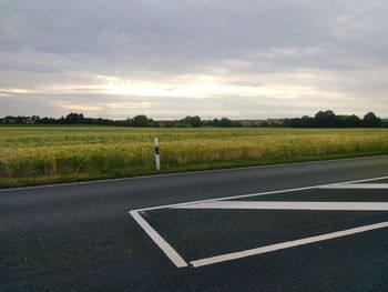 Road by field against sky