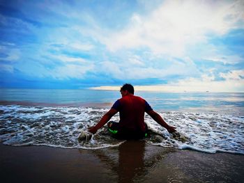 Rear view of man on beach against sky