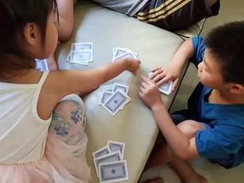 High angle view of siblings playing cards at home