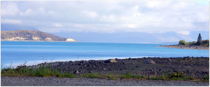 View of calm blue sea against cloudy sky