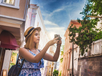 Young woman photographing against sky