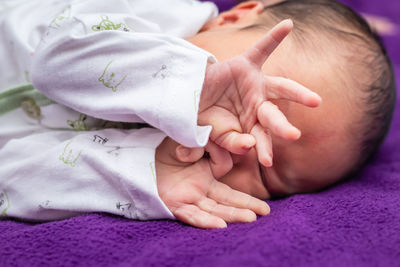 Newborn baby isolated sleeping in white cloth with purple background from different angle