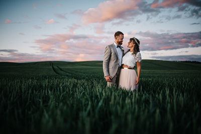 Rear view of couple on field against sky