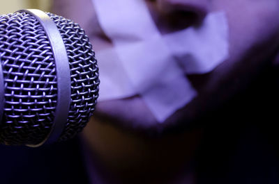 Cropped image of microphone against man with tape on mouth