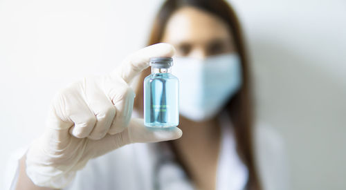 Close-up of doctor wearing mask holding liquid