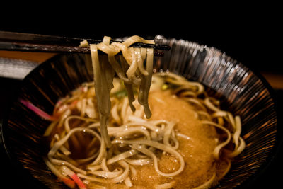 Chopsticks with noodles over bowl