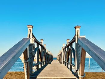 View of empty beach against clear blue sky