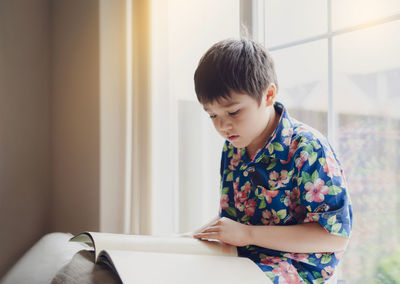 Boy looking away while standing on book