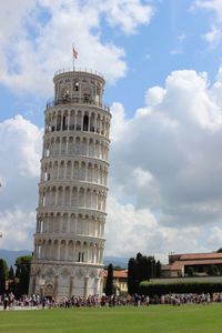 Tourists on top of historic building against cloudy sky