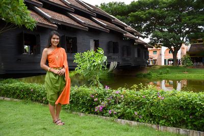 Full length of woman standing by house against building