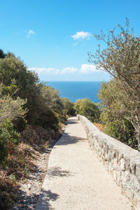 Footpath by sea against sky