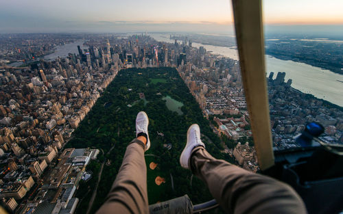 Low section of man sitting in helicopter over buildings in city