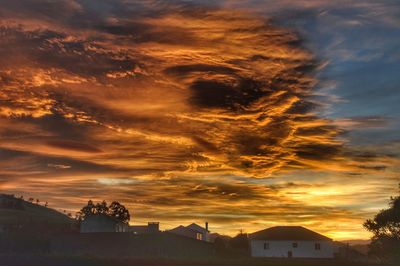 Silhouette houses against sky during sunset