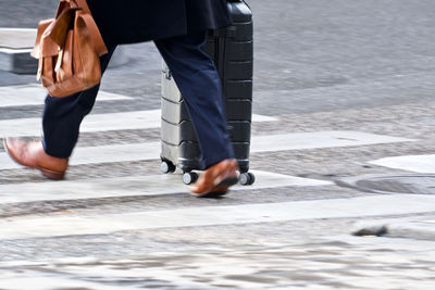 Low section of men walking on street in city