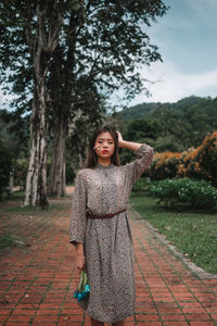 Portrait of a smiling young woman standing against trees