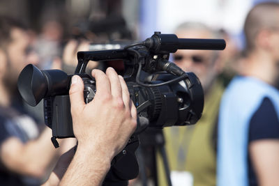 Close-up of cropped cameraman photographing crowd