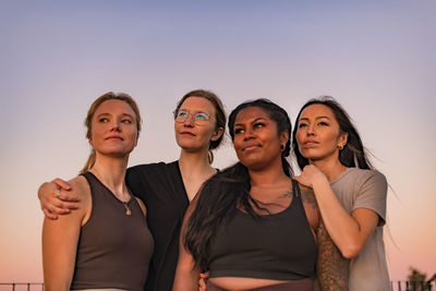 Portrait of smiling friends standing against clear sky