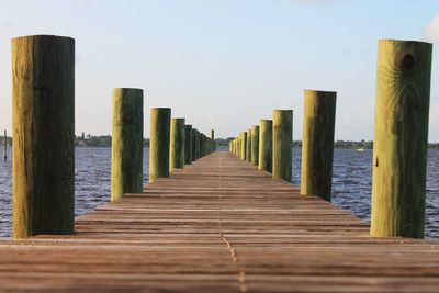 Empty wooden pier in lake against sky